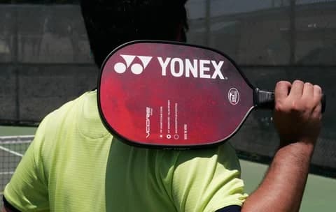 Red pickleball paddle held over a player's shoulder